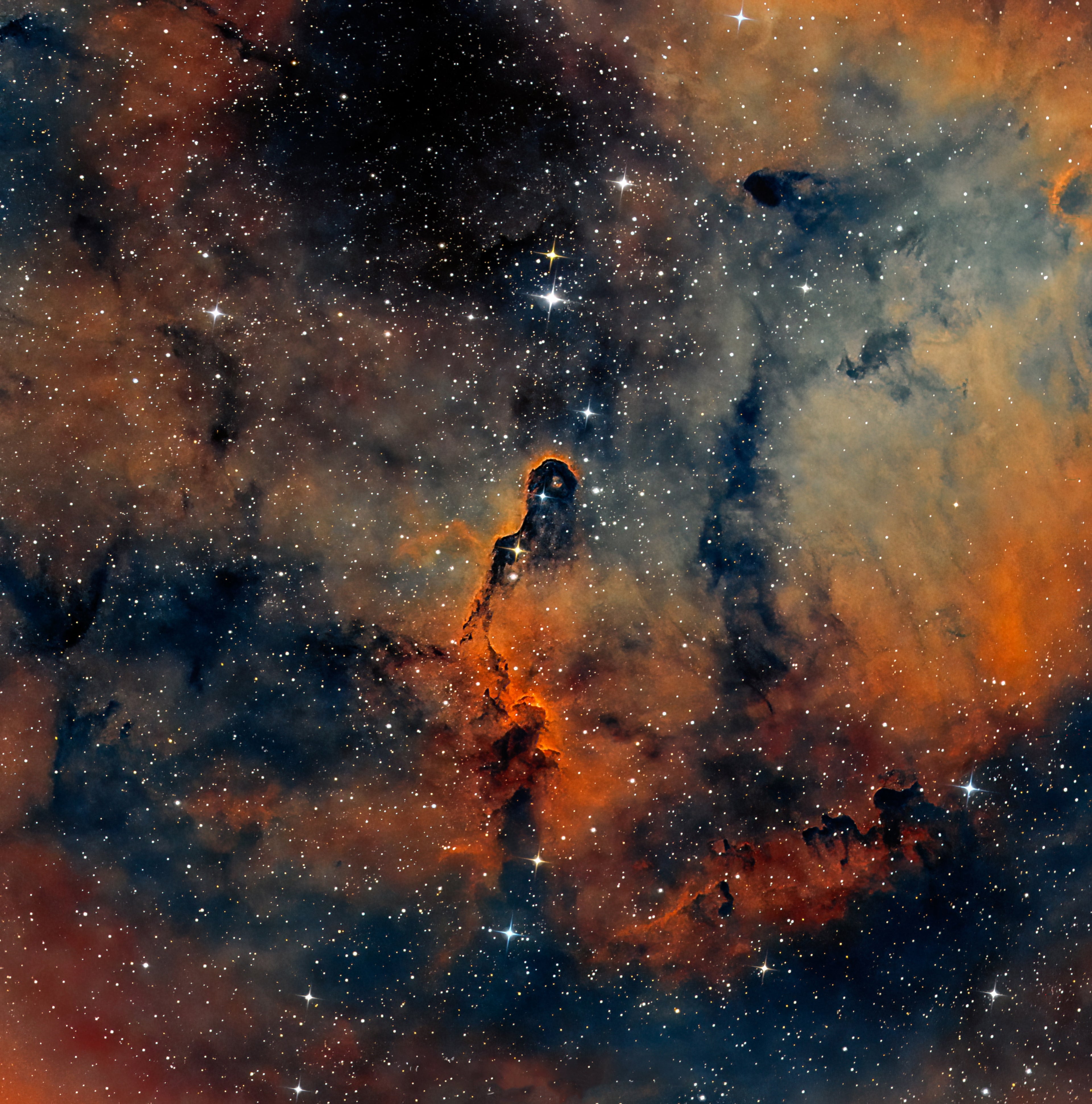 Elephant’s Trunk Nebula astrophotography IC 1396 showing pillar of gas and dust resembling a silent watcher figure in glowing red, gold, and green interstellar clouds.