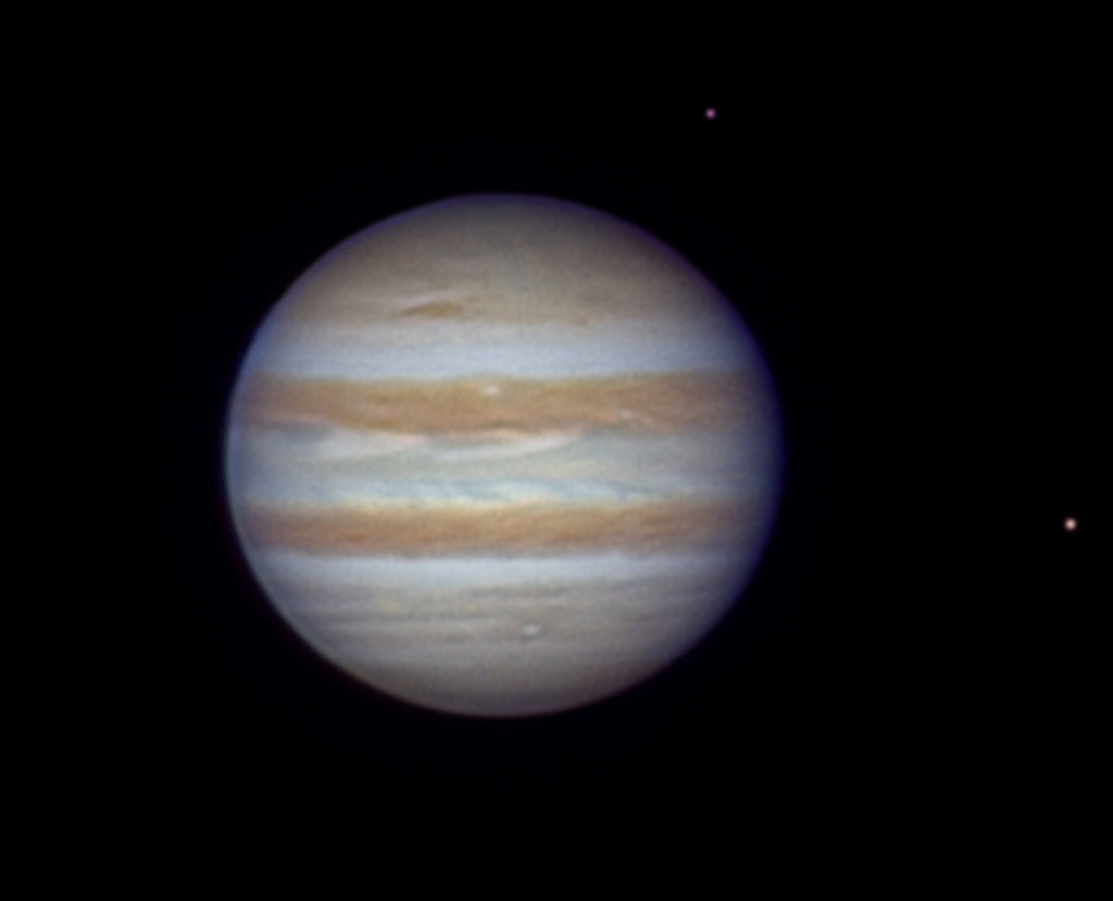 High-resolution image of Jupiter with Europa and io visible, showing atmospheric cloud bands and orbital alignment. 